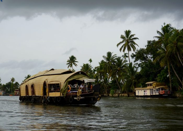 Scenic view of a traditional Kerala houseboat cruising through lush backwaters.